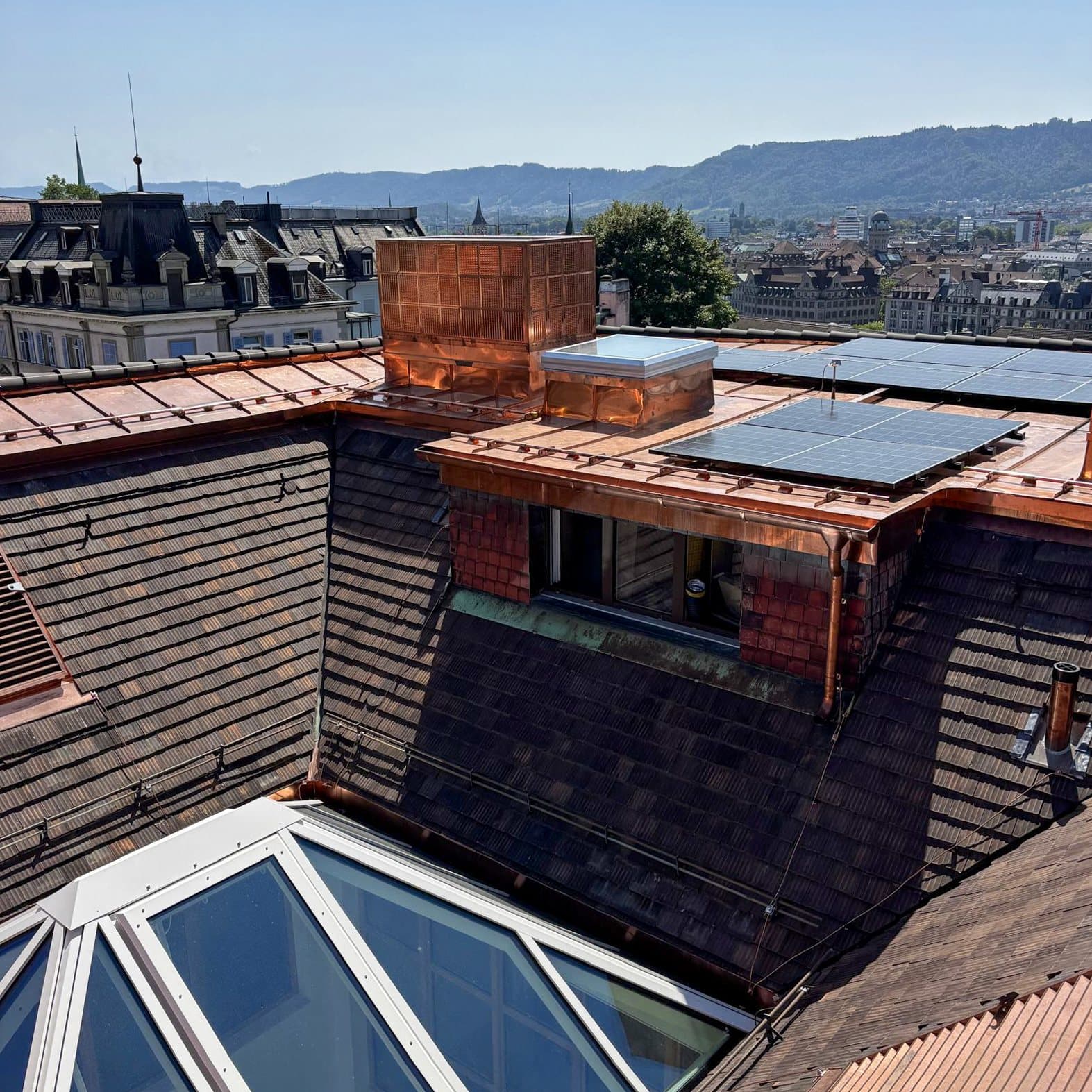 Dachlandschaft mit Kupferverkleidung, Photovoltaik und Blick über Zürich