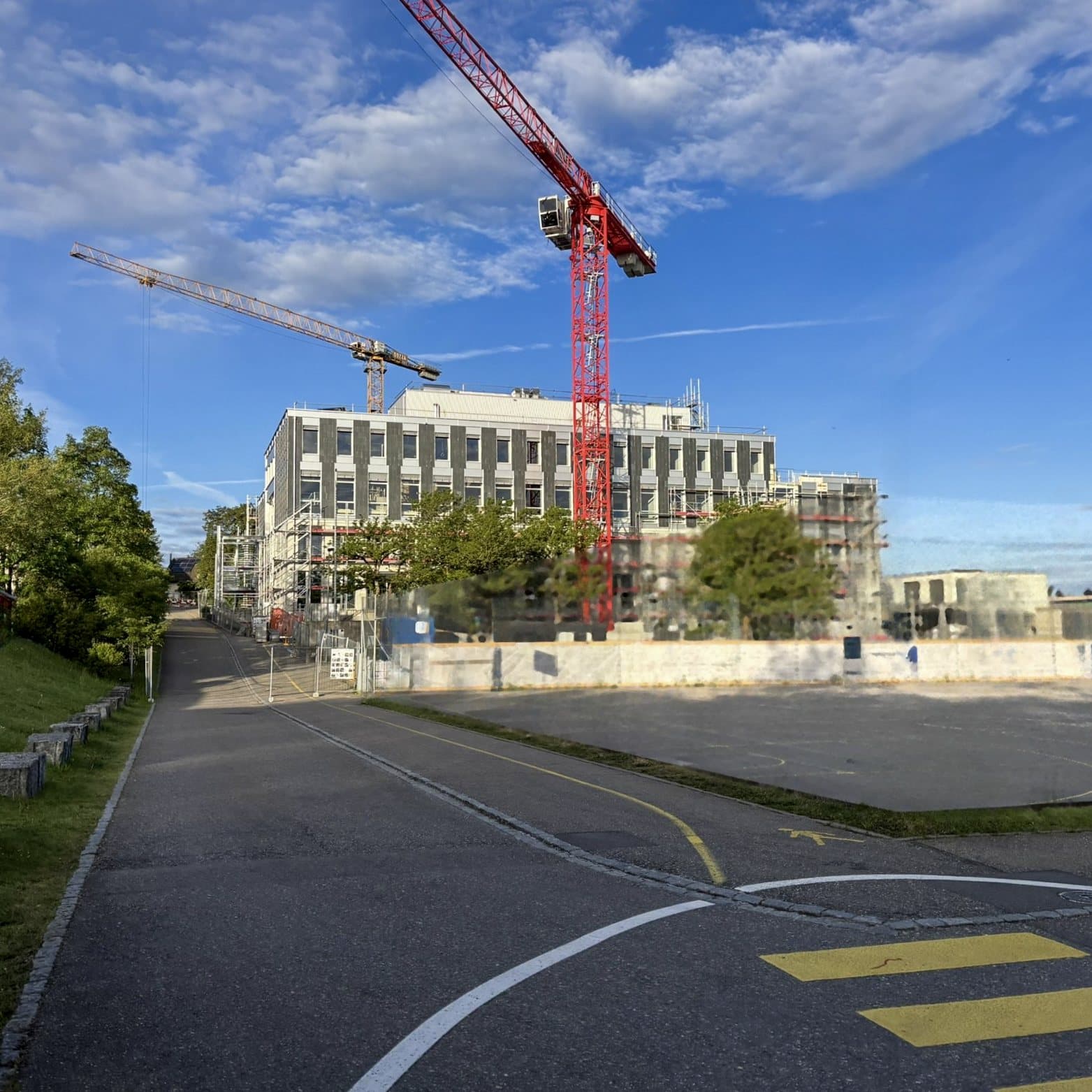Baustelle ICS Zumikon mit Kranen und eingerüstetem Neubau